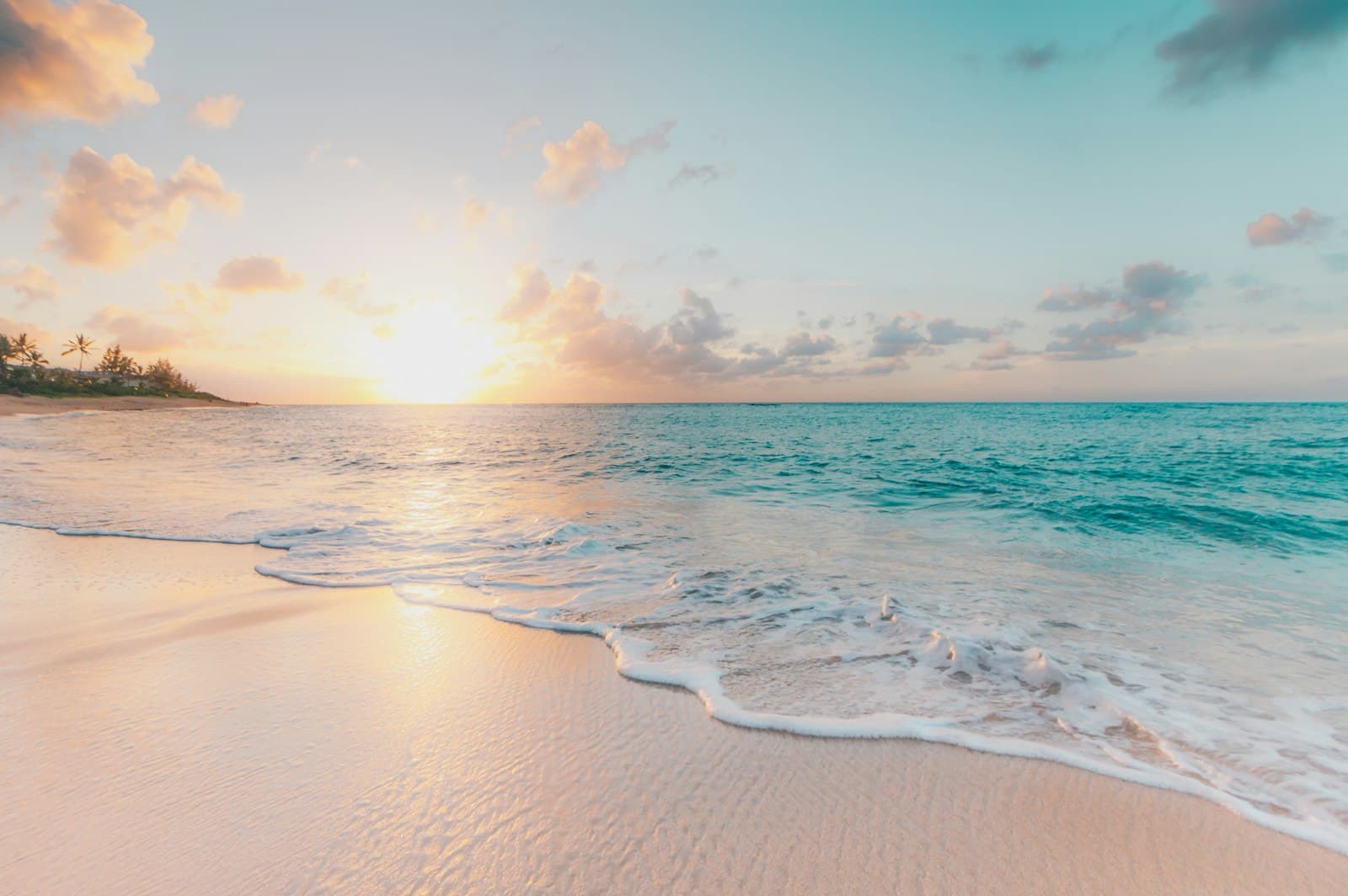 Turquoise Gulf water meeting white sand at sunset