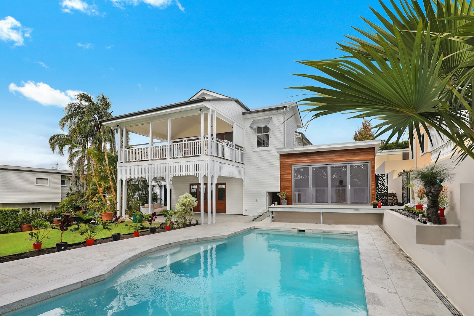 White two-story Florida home with palms and a pool